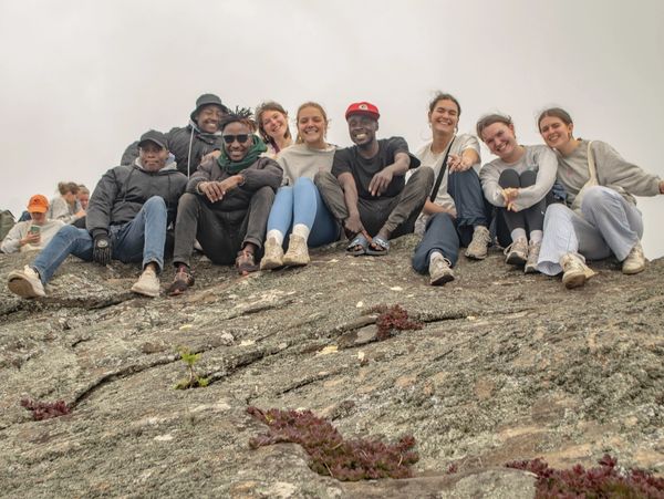 Een groepje vrienden zit op een rotsachtige heuvel in Taita Taveta, glimlacht en geniet van het moment.