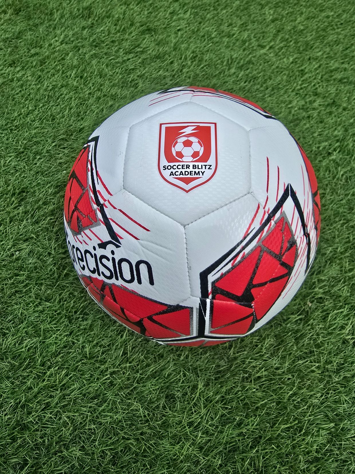 White and red soccer ball on grass.