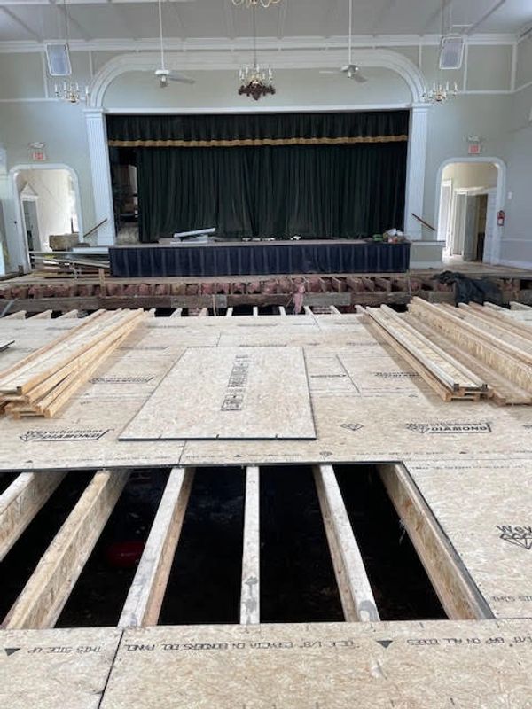 flooring under layment and joists with stage in background.