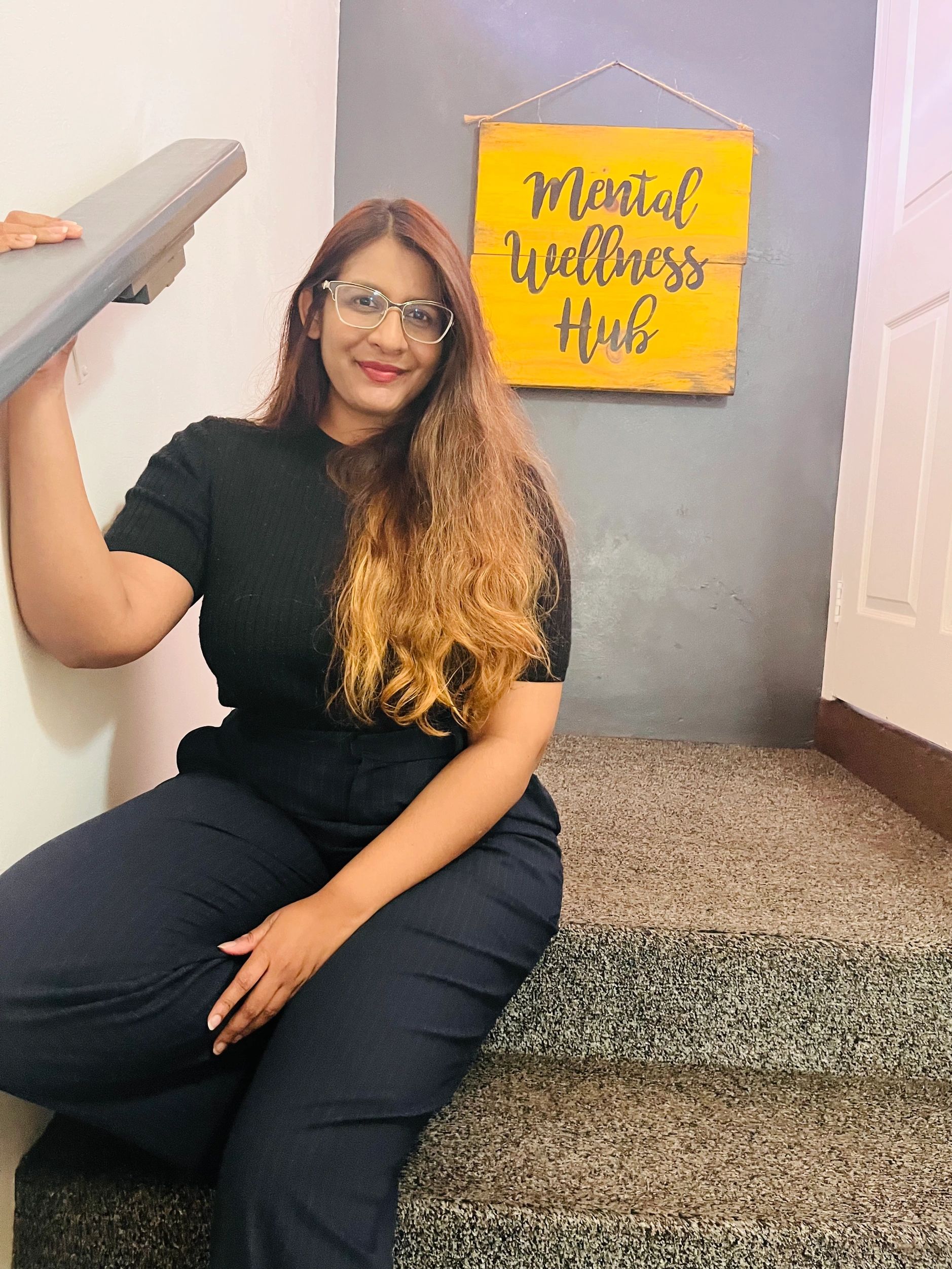 Woman sitting on stairs near a sign that reads "Mental Wellness Hub."