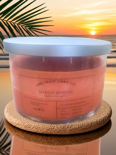 A tropical mango-scented candle with a sunset beach background.
