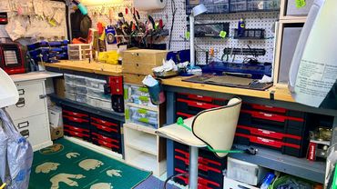 Organized workshop with tools, drawers, and a tied chair.