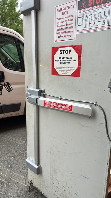 Emergency exit door with multiple warning signs and a panic bar.