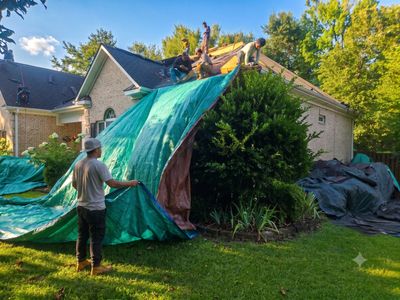 People covering a roof with tarps.