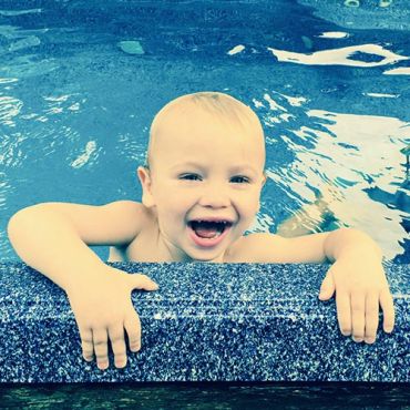 Happy child smiling in a pool.