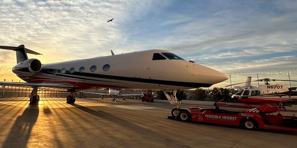 A futuristic white aircraft on a runway during sunset with a red fire truck nearby.