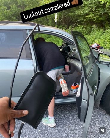 Person completing a lockout on a car door with a tool.
