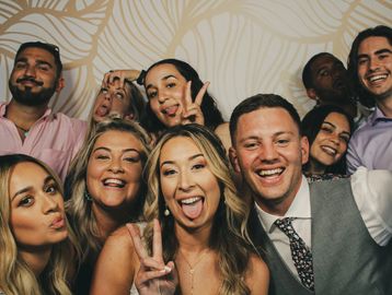 Wedding couple along with large group of friends posing for the photo booth.