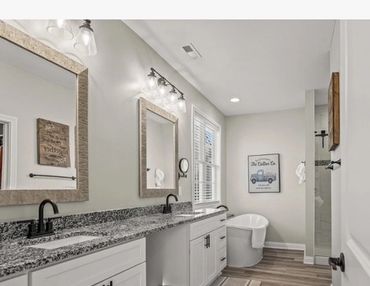 Modern bathroom with dual sinks, granite countertop, and wooden framed mirrors.