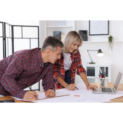 Two architects collaborating on a project using laptop and drawings.