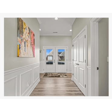 Bright hallway with double white doors and colorful wall art.