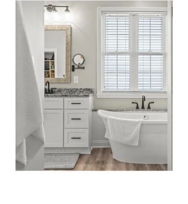 Bright, modern bathroom with a white bathtub and granite countertop.