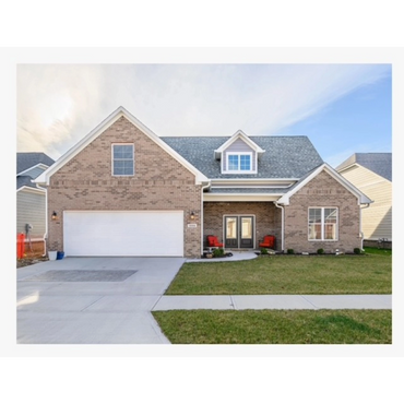 Modern brick house with a double garage and a porch with red chairs.