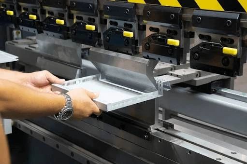 Person operating a metal sheet bending machine.