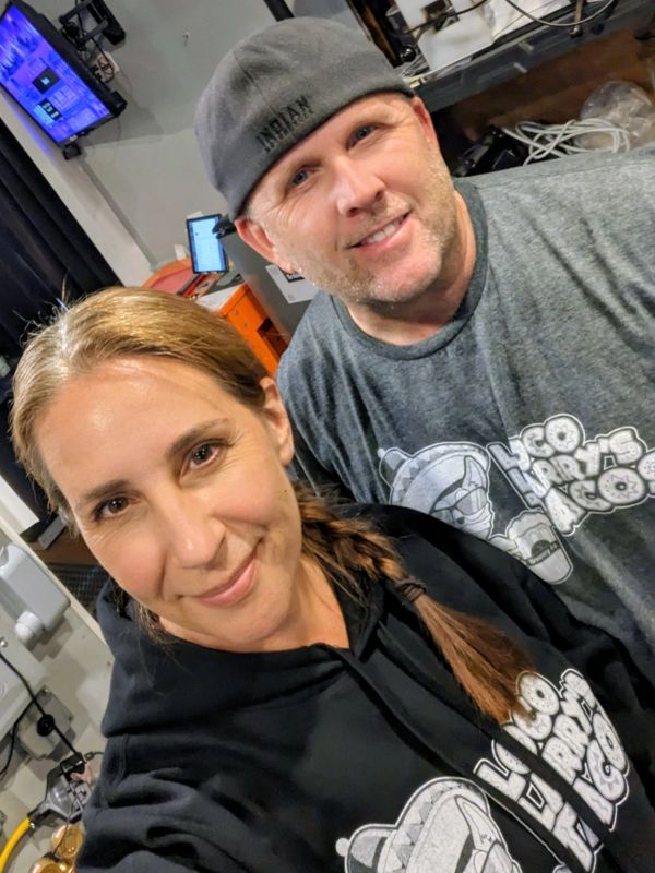 Two smiling people wearing matching 'Loco Por Tacos' shirts.
