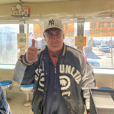 Man wearing a Yankees hat, showing a thumbs up