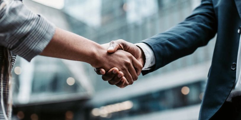 Two people shaking hands in a business setting.