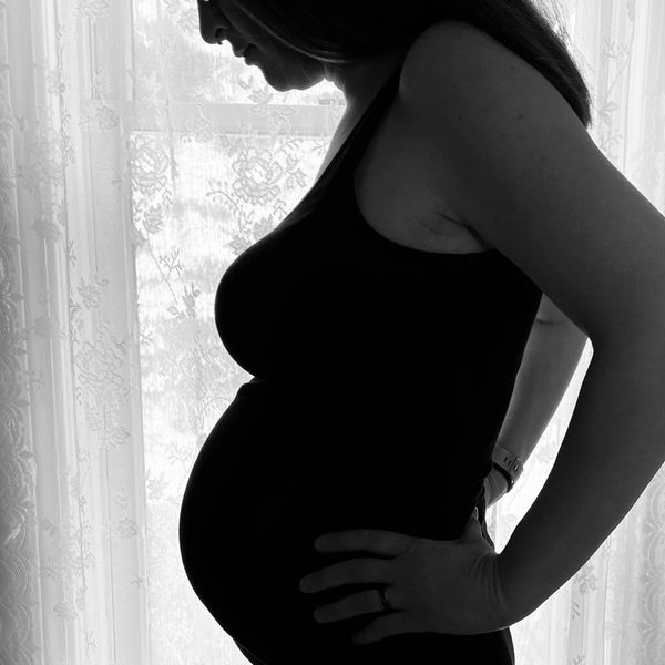 Pregnant mom looking down at her belly.