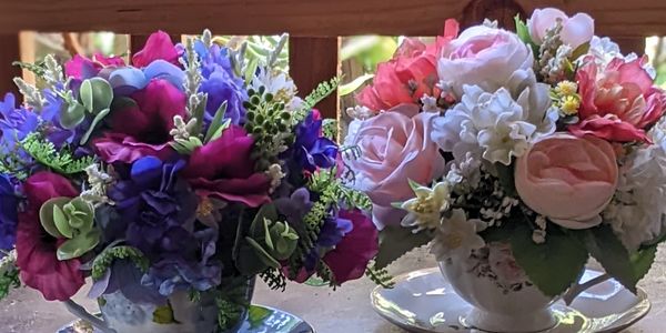 Two teacups with vibrant flower arrangements.