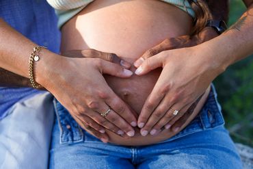 Hands forming a heart shape on a pregnant belly, symbolizing love and anticipation.