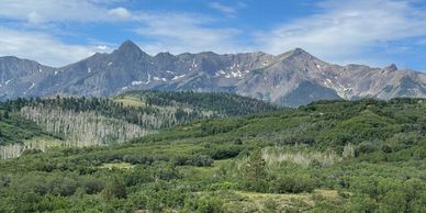 A scenic mountain range with green hills and a partly cloudy sky.