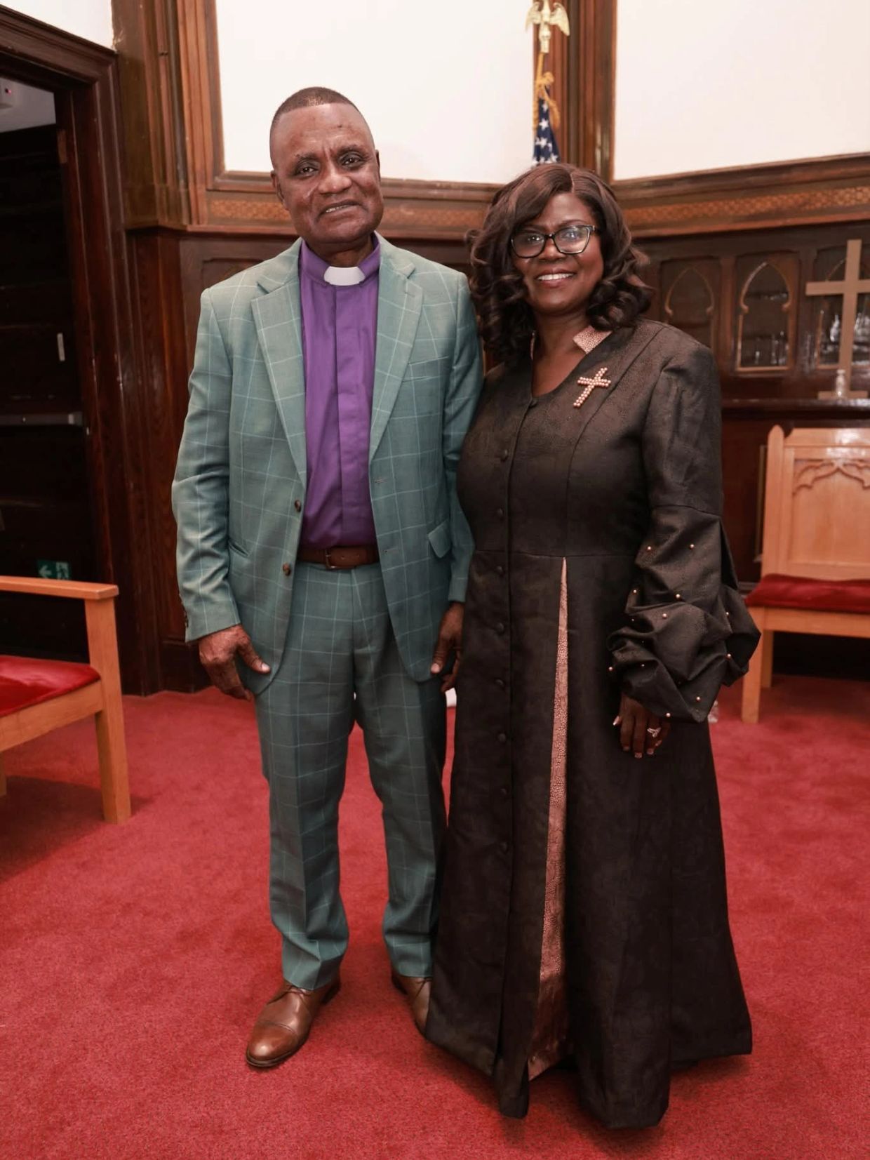Two people posing inside a church.