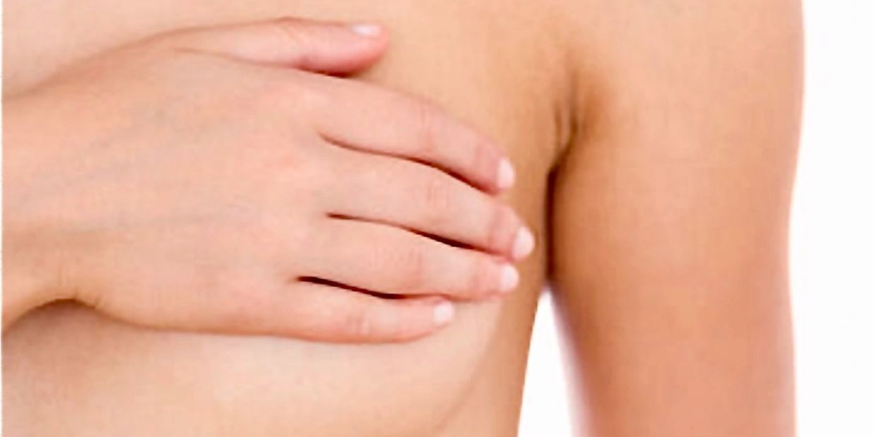 A person covering their breast with one hand.