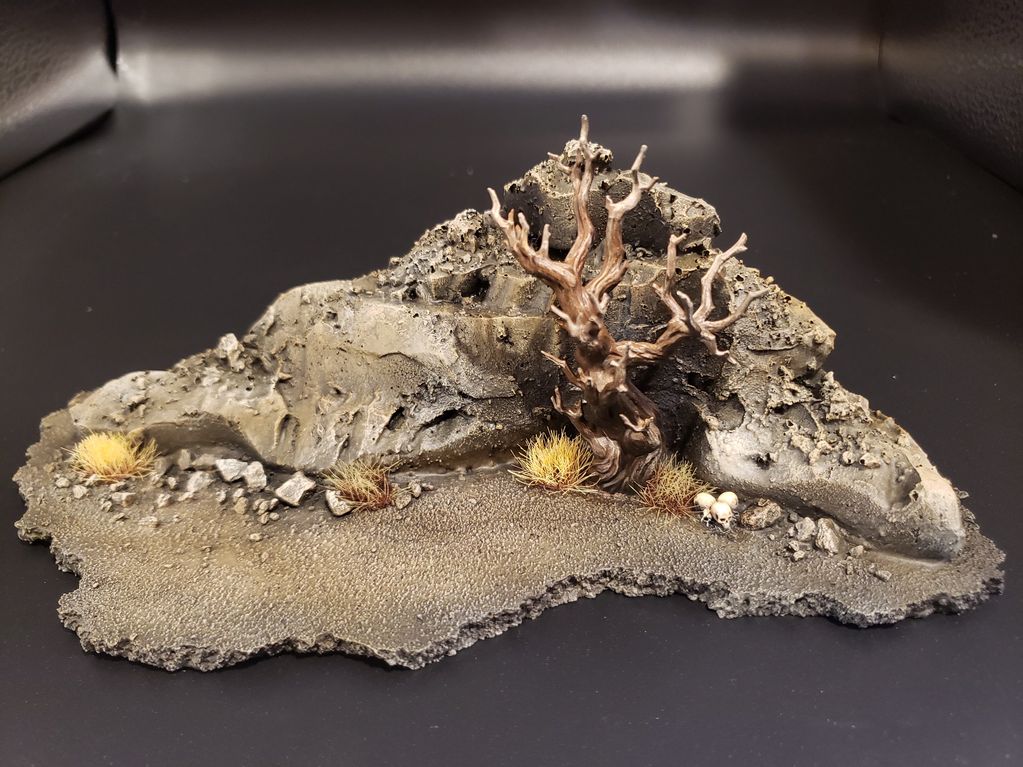 Miniature diorama featuring a barren tree, rocky terrain, and skulls.