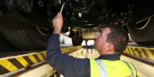 An engineer conducting a mechanical maintenance under a truck