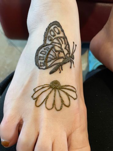 Butterfly and flower henna ink on woman's foot