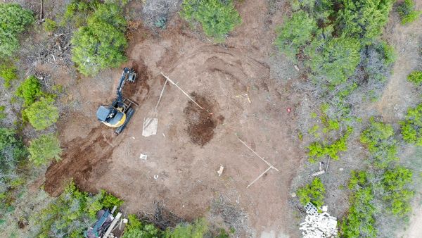 Aerial view of a construction site in a forest clearing with an excavator.