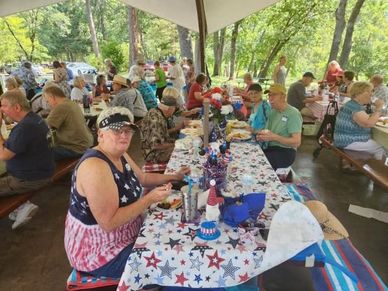 People enjoying a patriotic picnic under a pavilion.