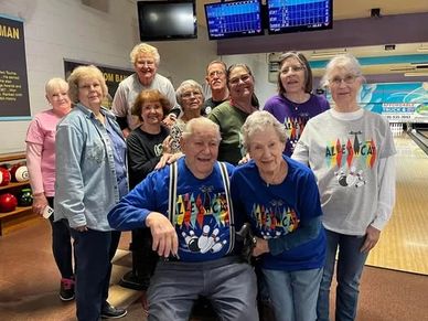 Group of seniors posing happily at a bowling alley.