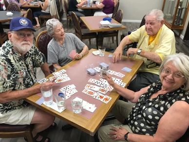 Four seniors enjoying a lively card game together at a community center.