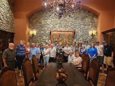 Group of people gathered in a rustic dining room with stone walls.
