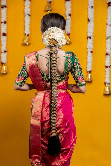 Woman in traditional South Indian attire with elaborate hair decorations and floral garlands.