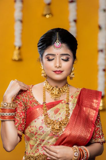 A woman in traditional Indian bridal attire with gold jewelry and a red saree.