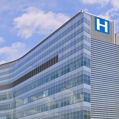 Modern hospital building with glass exterior and blue sky.