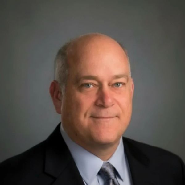 Professional headshot of a middle-aged man in a suit.