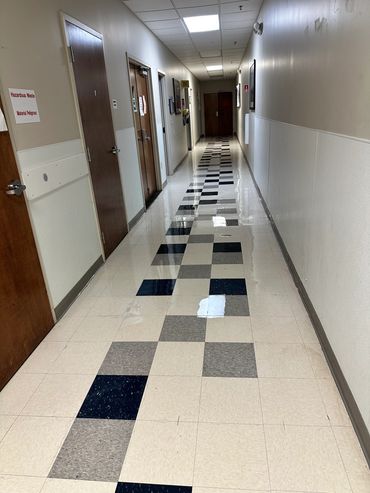A clean hallway with checkered floor tiles and closed wooden doors.