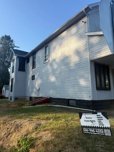 White house exterior with a pressure washing service sign in front.