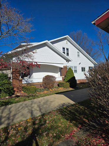 Bright white house with a clear blue sky and autumn foliage.