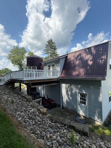 A house with a wooden deck and a rocky garden under a cloudy sky.