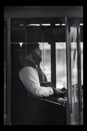 Man wearing a beanie and glasses sitting inside a vehicle.