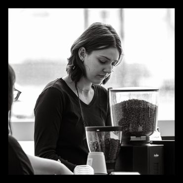 A woman focused on coffee preparation in a cafe setting.