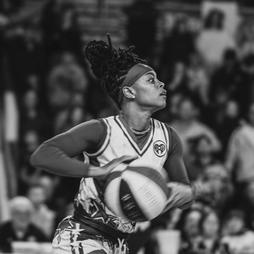 Female basketball player intensely preparing to pass the ball during a game.