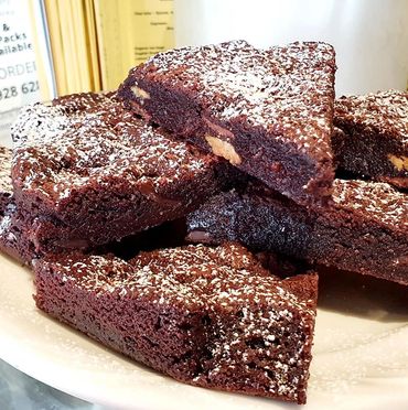 Delicious chocolate brownies, dusted with powdered sugar, stacked on a plate.