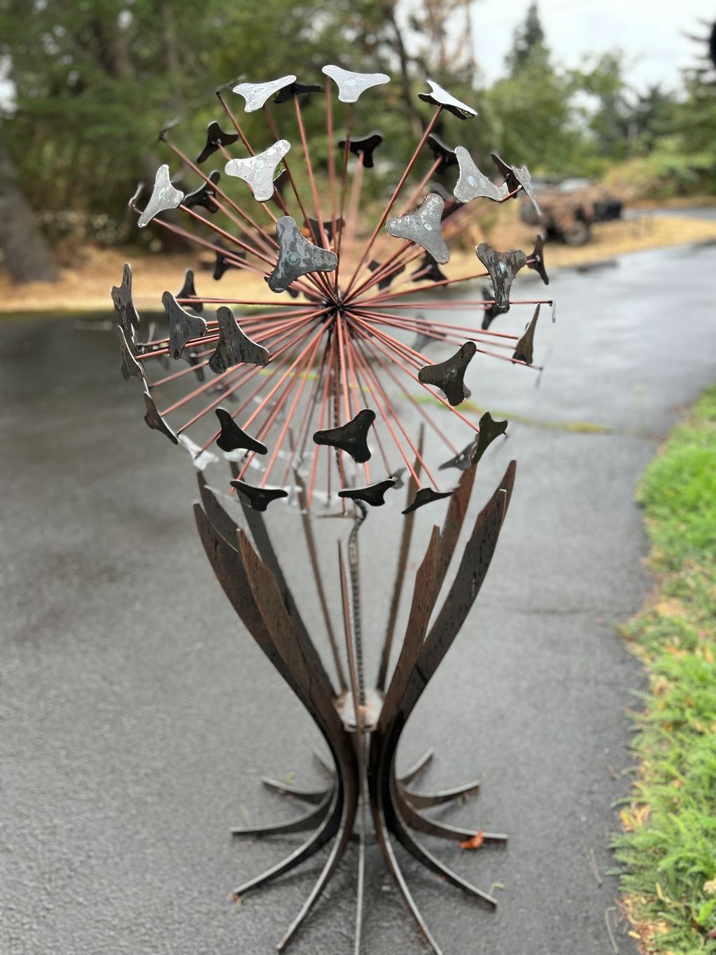Metal sculpture resembling a dandelion with intricate petal-like structures.
