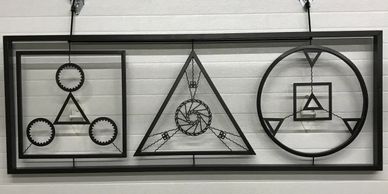 Black metal geometric wall art with circles, triangles, and squares in a rectangular frame.