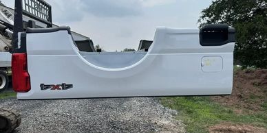 White truck bed side panel with 4x4 badge placed outdoors.